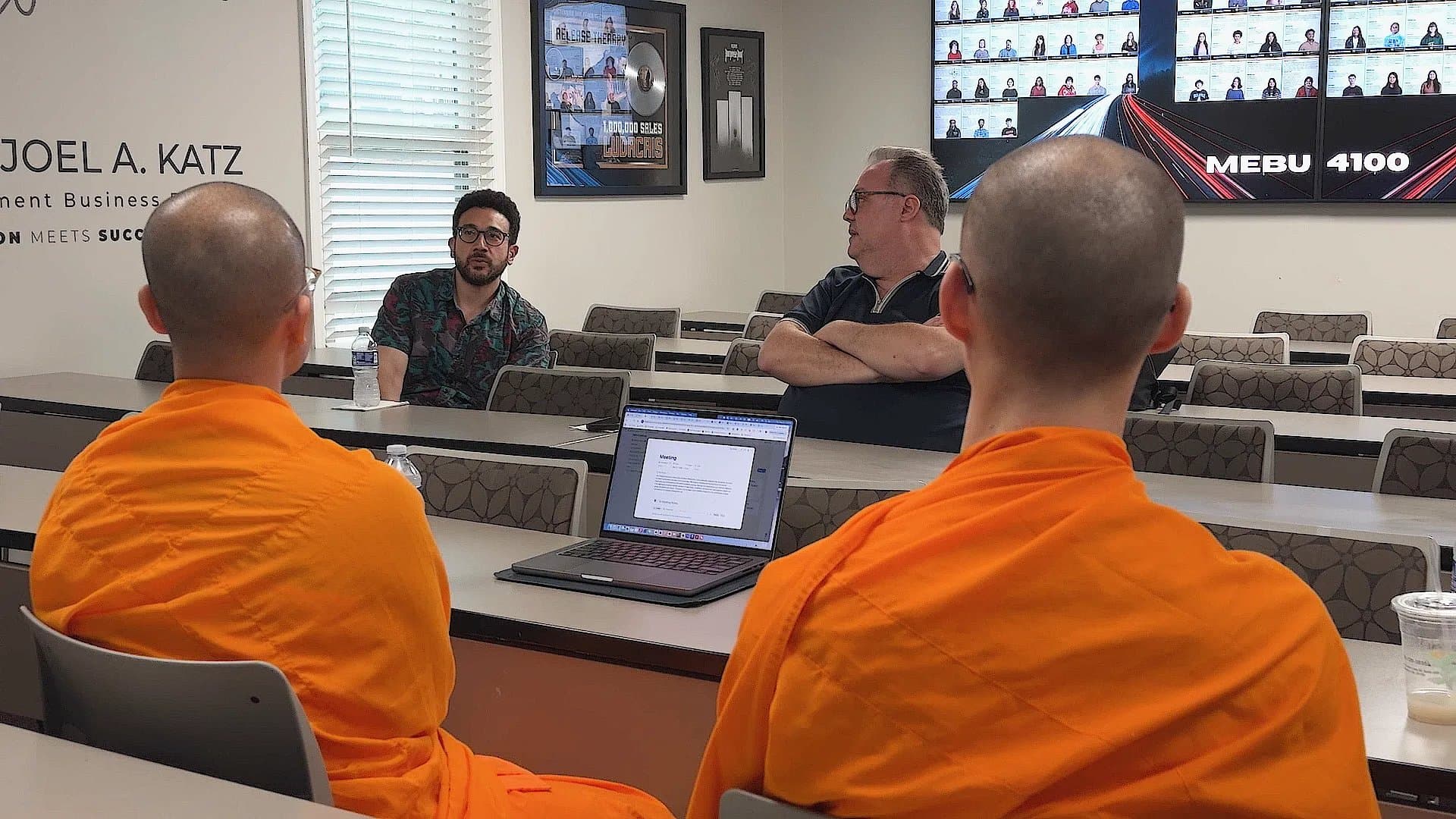 The two monks in a meeting with two faculty members in a university classroom.
